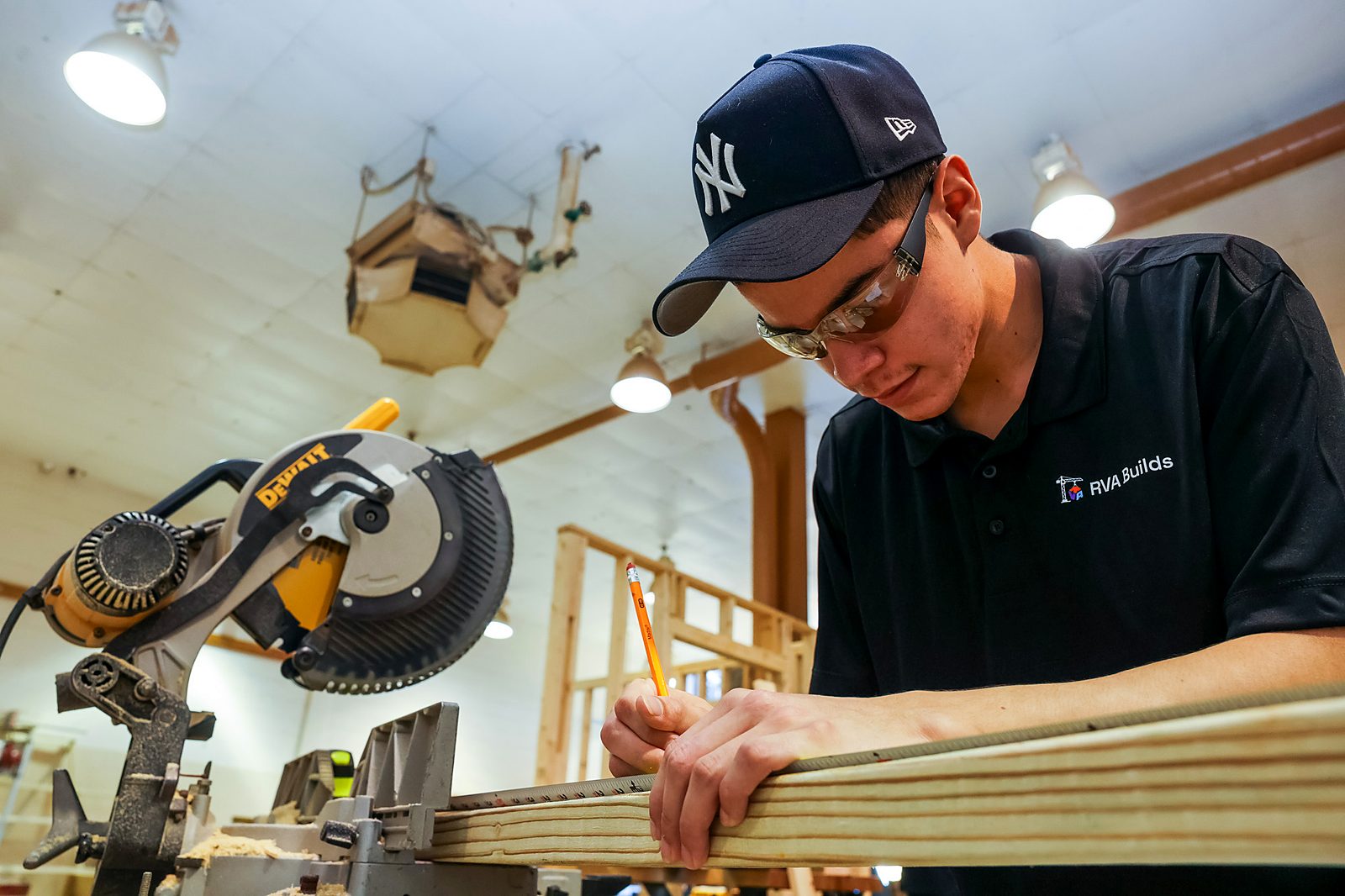 An RVA Builds student marking a board at a miter saw