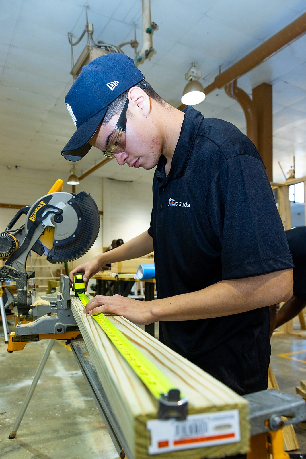 An RVA Builds student measuring lumber in a carpentry shop